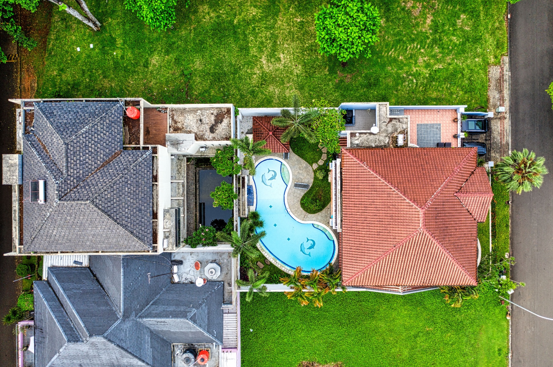 Aerial of two homes with pool between lush yards