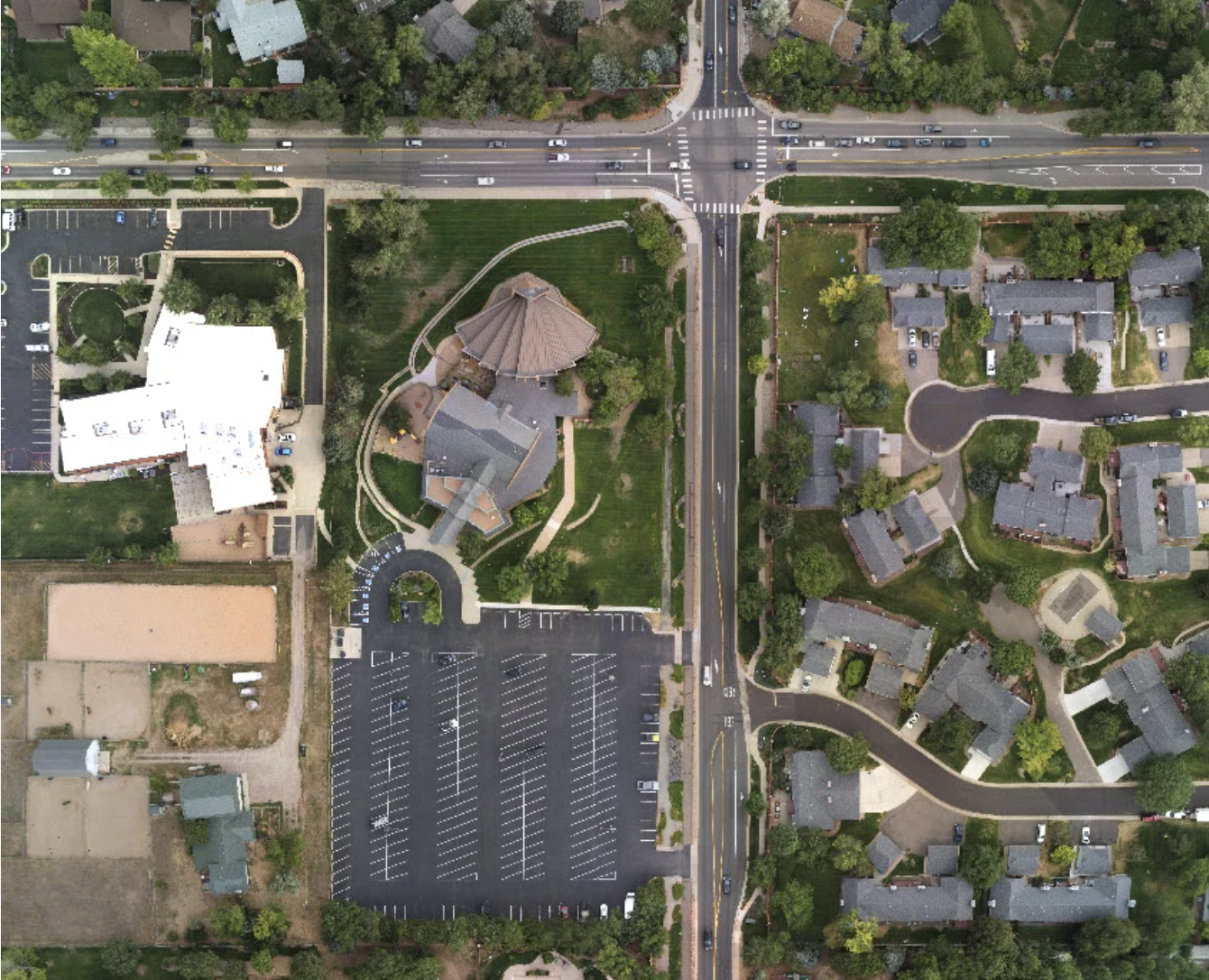Top-down aerial map of a residential area showing streets, homes, parking lots, a community building and surrounding landscaping