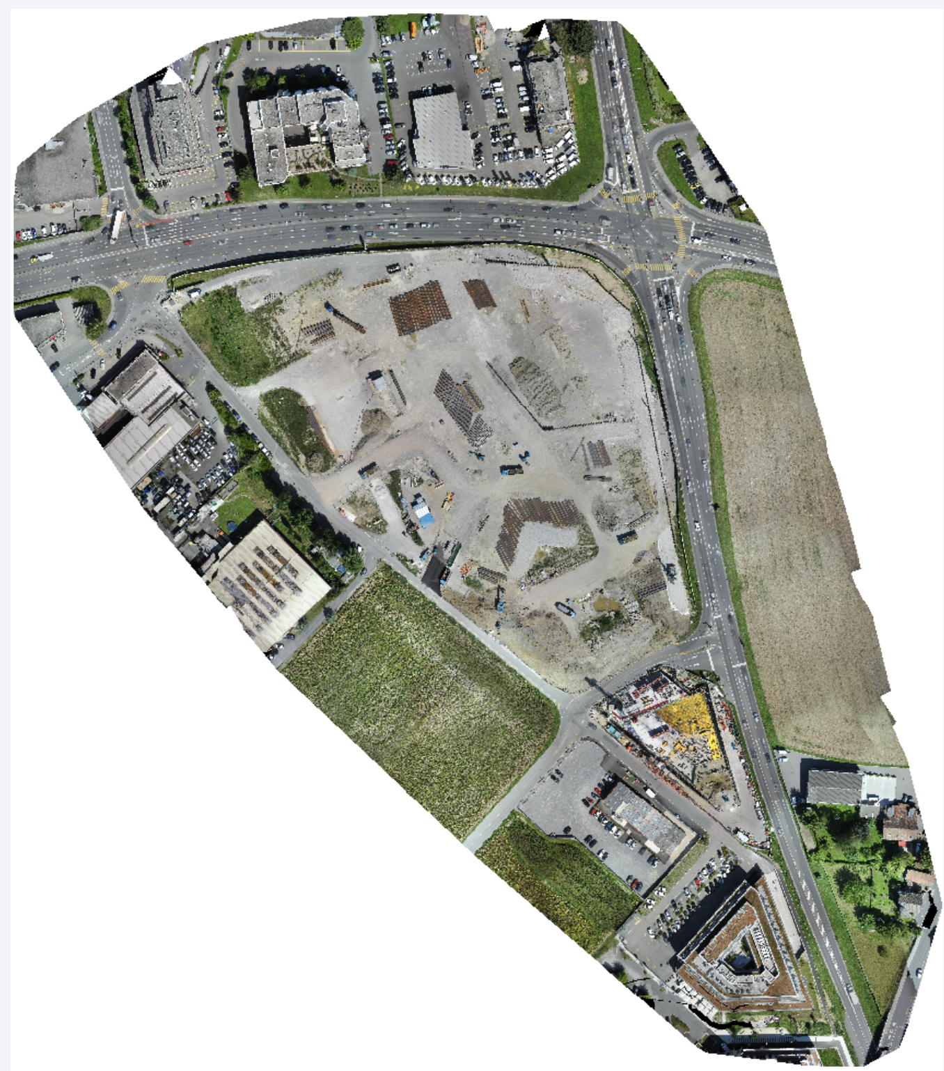 Top-down orthomosaic of an active construction site and the surrounding roads, buildings and fields