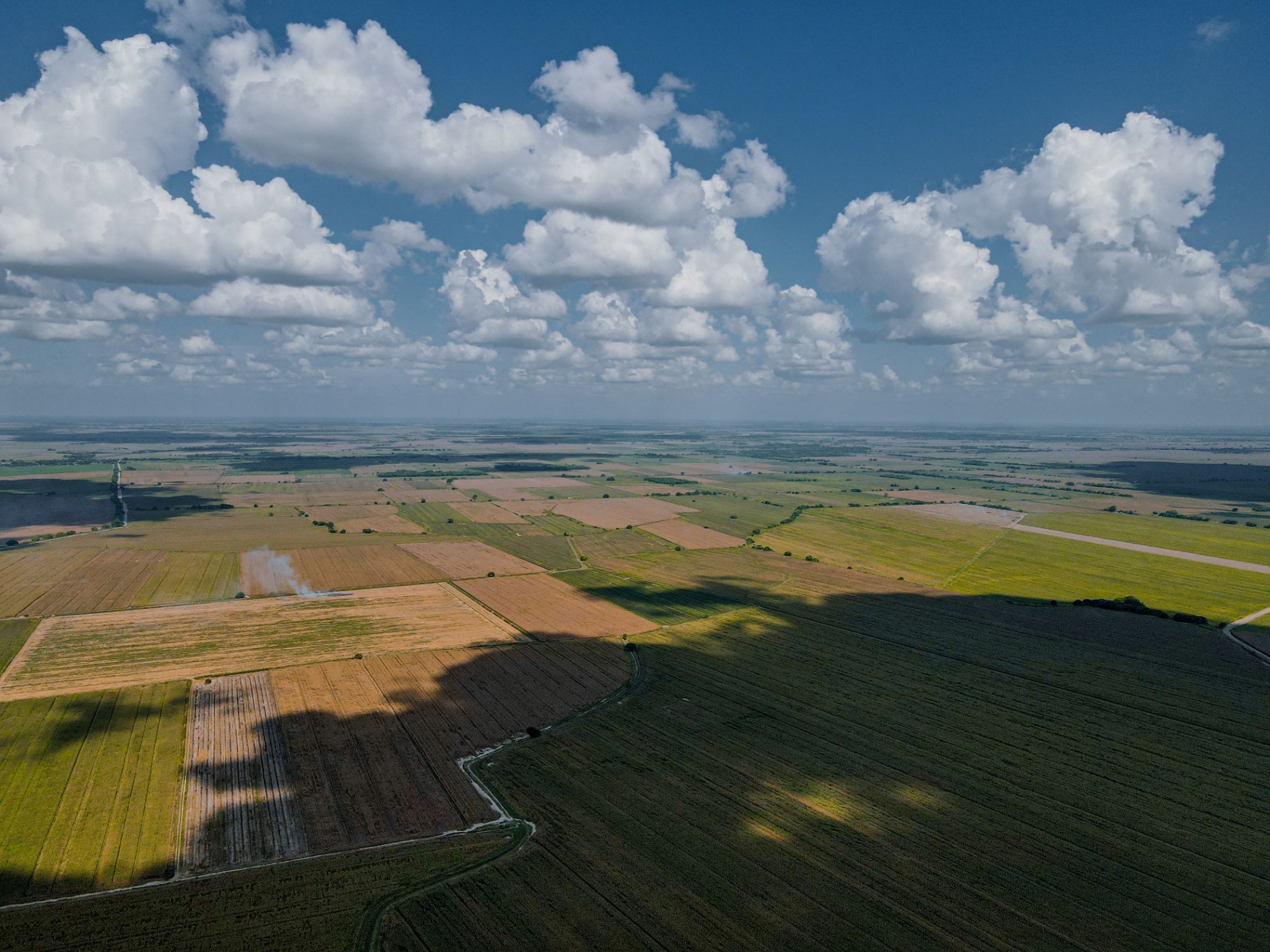 Aerial of expansive farmland with cloud shadows
