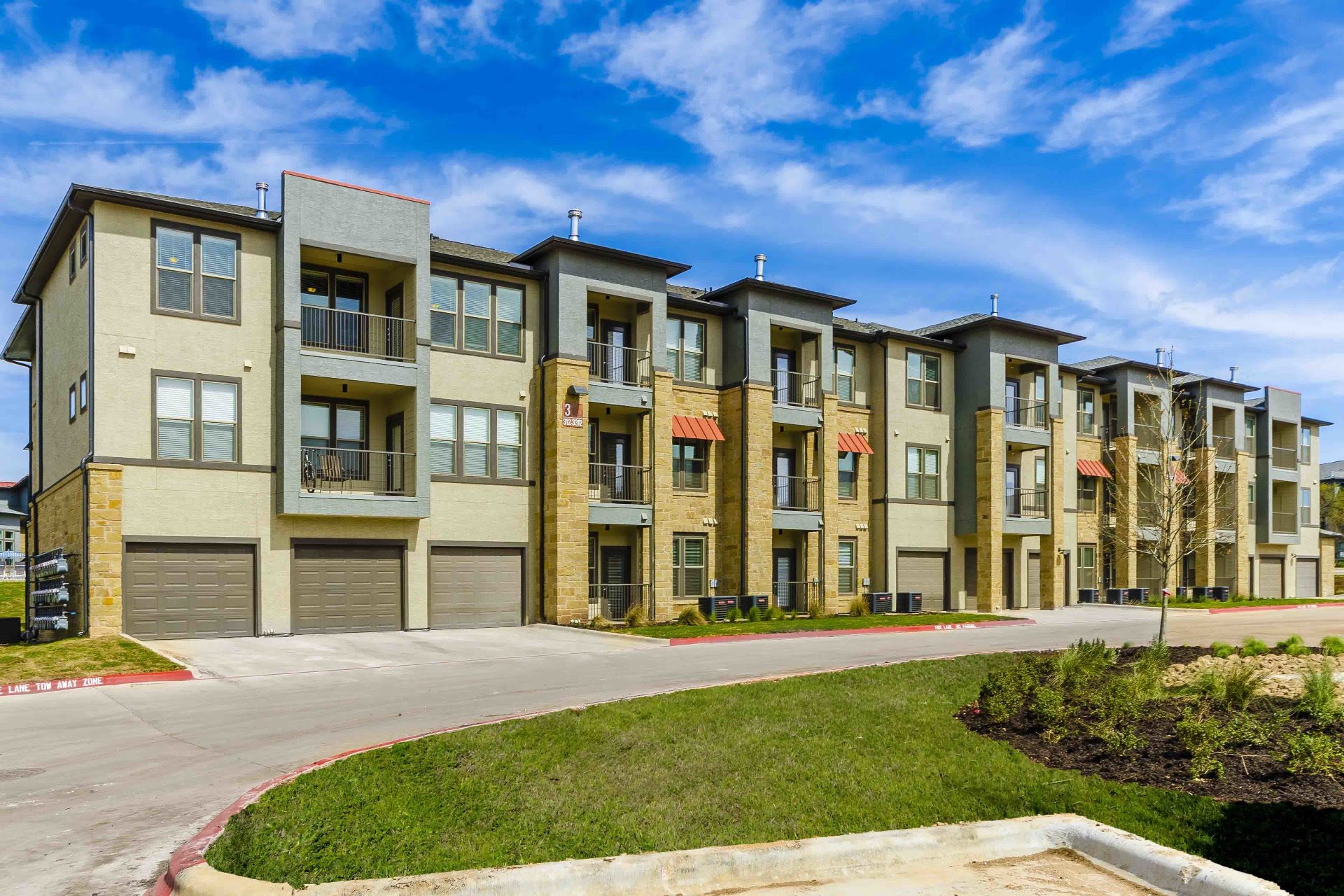Three-story apartment building with stone accents and tuck-under garages